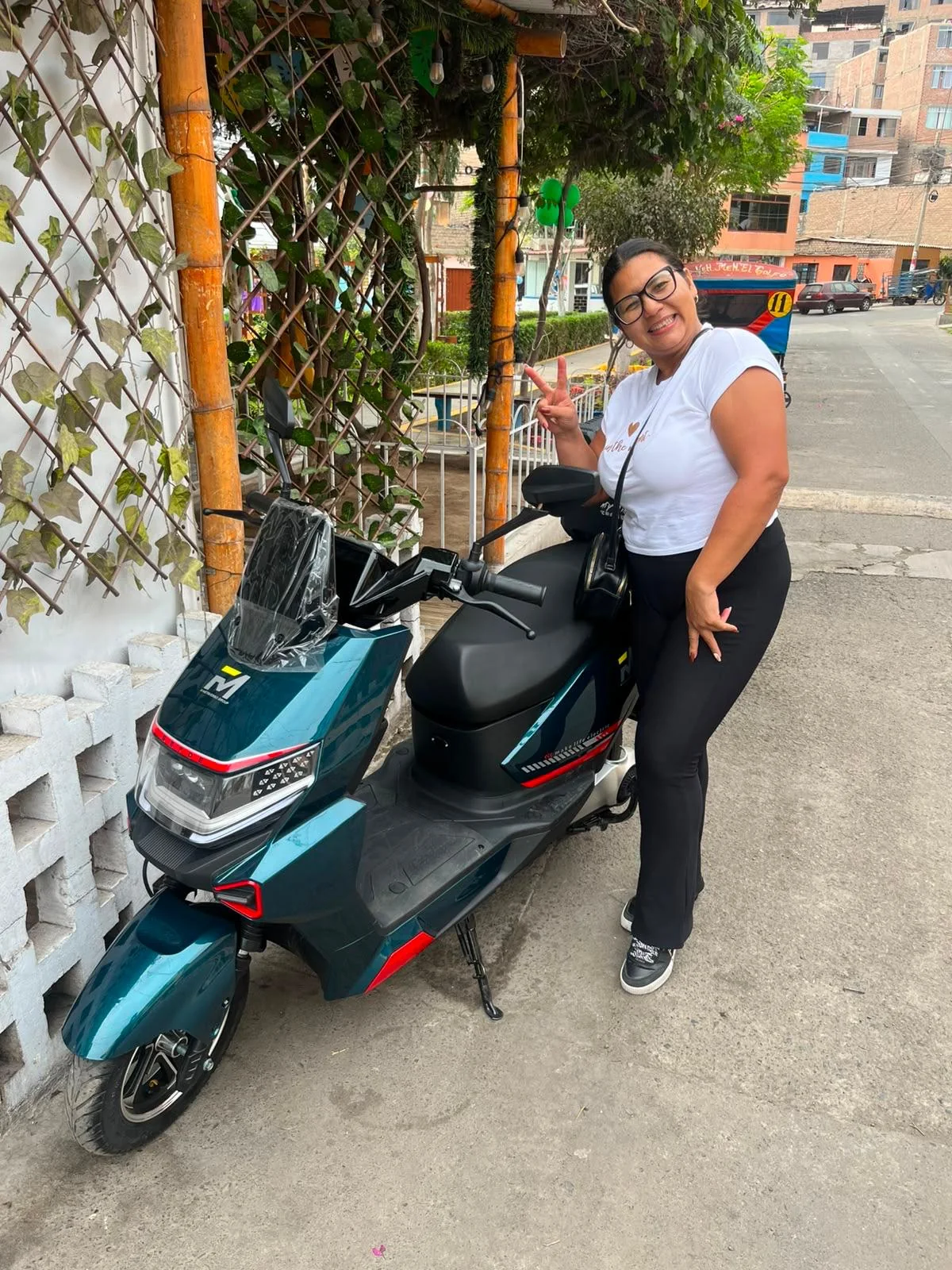 Clienta Dorcas junto a scooter electrico verde